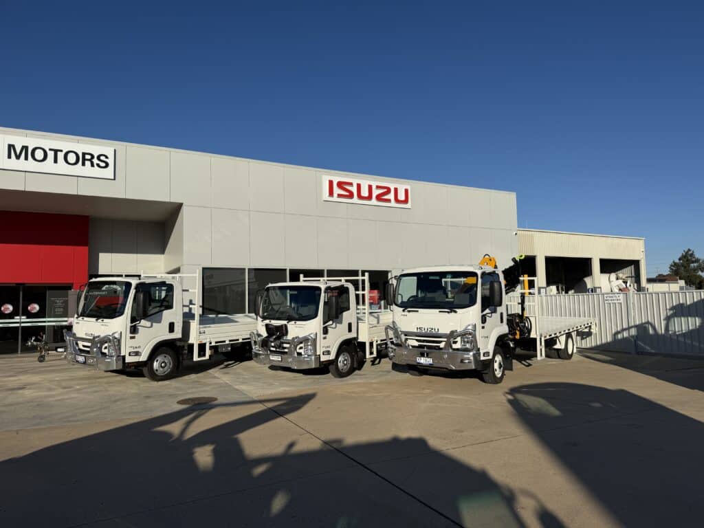 Three trucks parked out the front of a building.